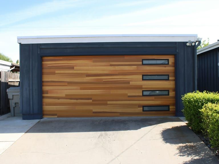 A new wood-panel garage door on a dark blue detached garage.