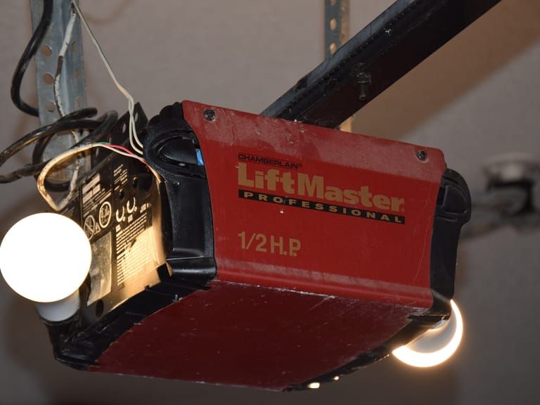 An old ceiling-mounted garage door opener with its bulbs on.