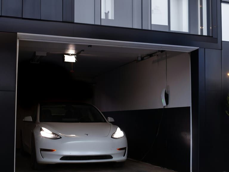 A garage door standing wide open after dark with a car parked inside.